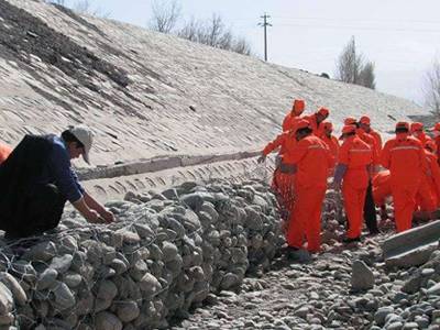 Several workers are placing the sack gabion at the foot of dam.