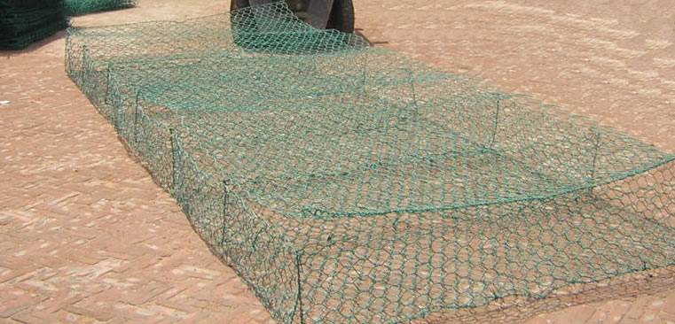 A mechanically woven double twisted hexagonal green PVC coated gabion reno mattress on the ground.
