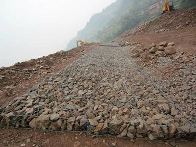 Two machines are working in the construction site and several gabion mattress on the ground.