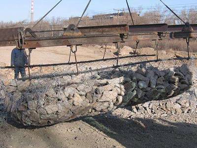 A machine is holding the sack gabion, which is filled with stones.